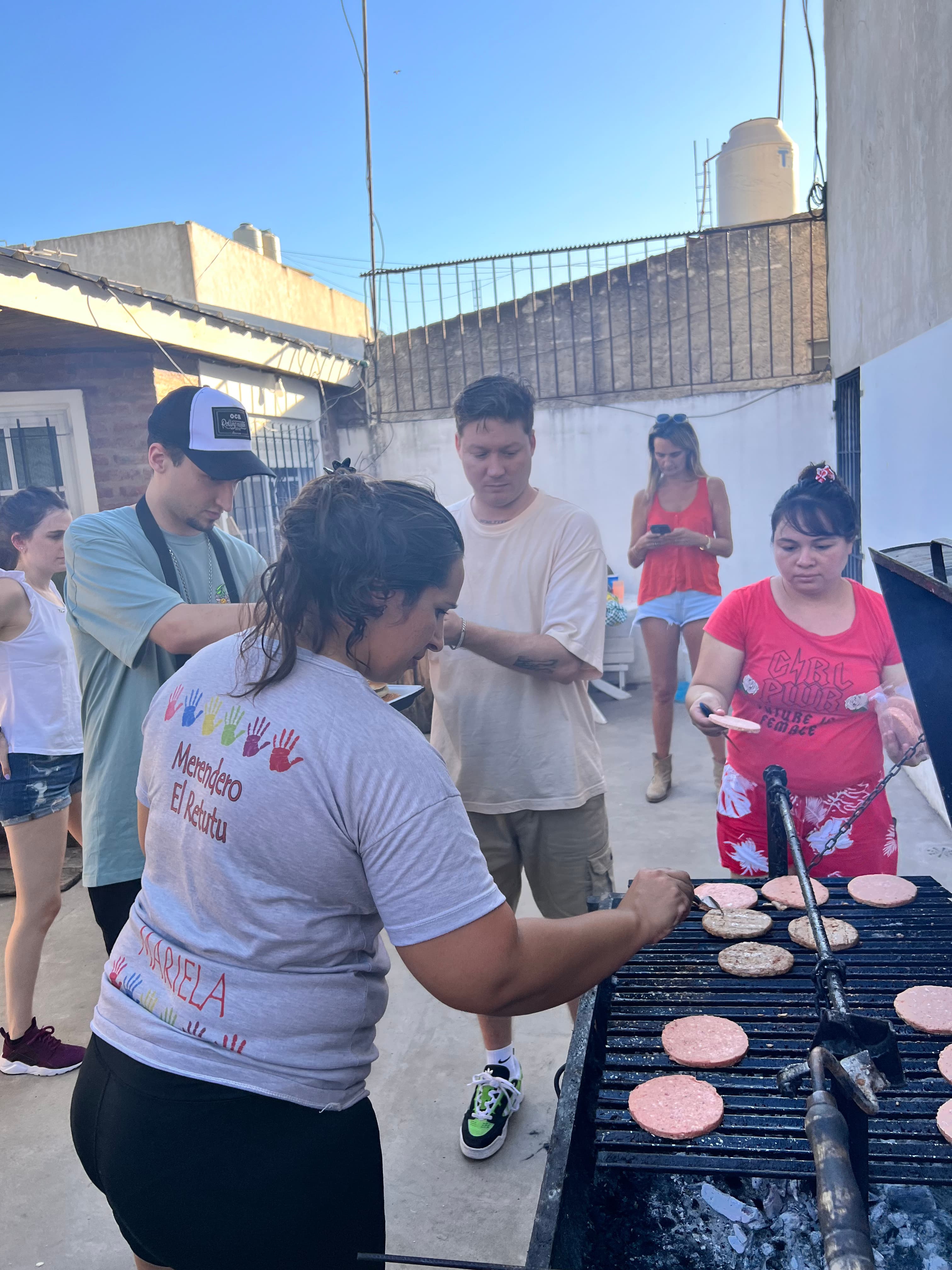 Voluntarios cocinando hamburguesas a la parrilla en una terraza