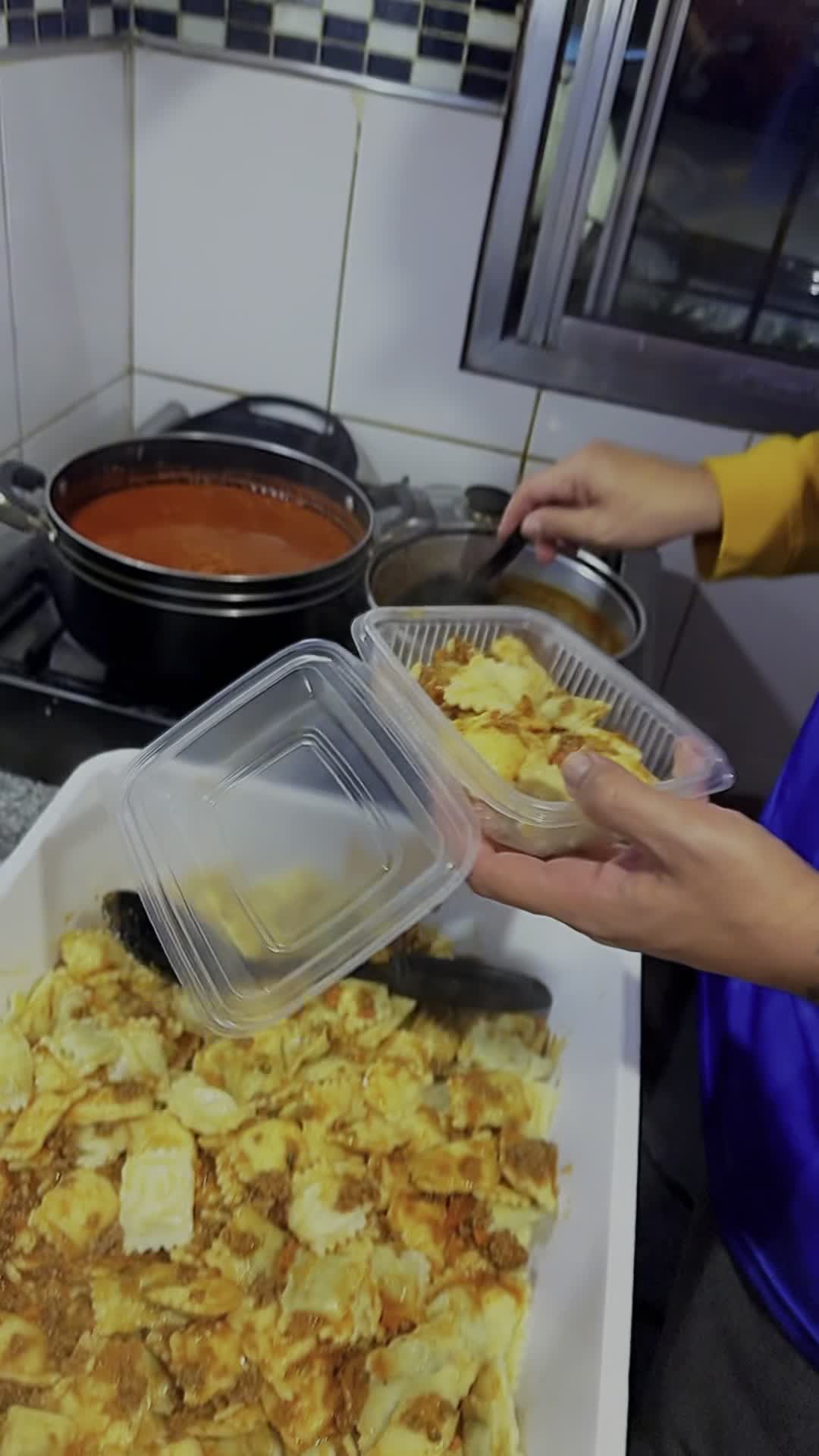 Preparando las viandas con ravioles y salsa boloñesa para repartir