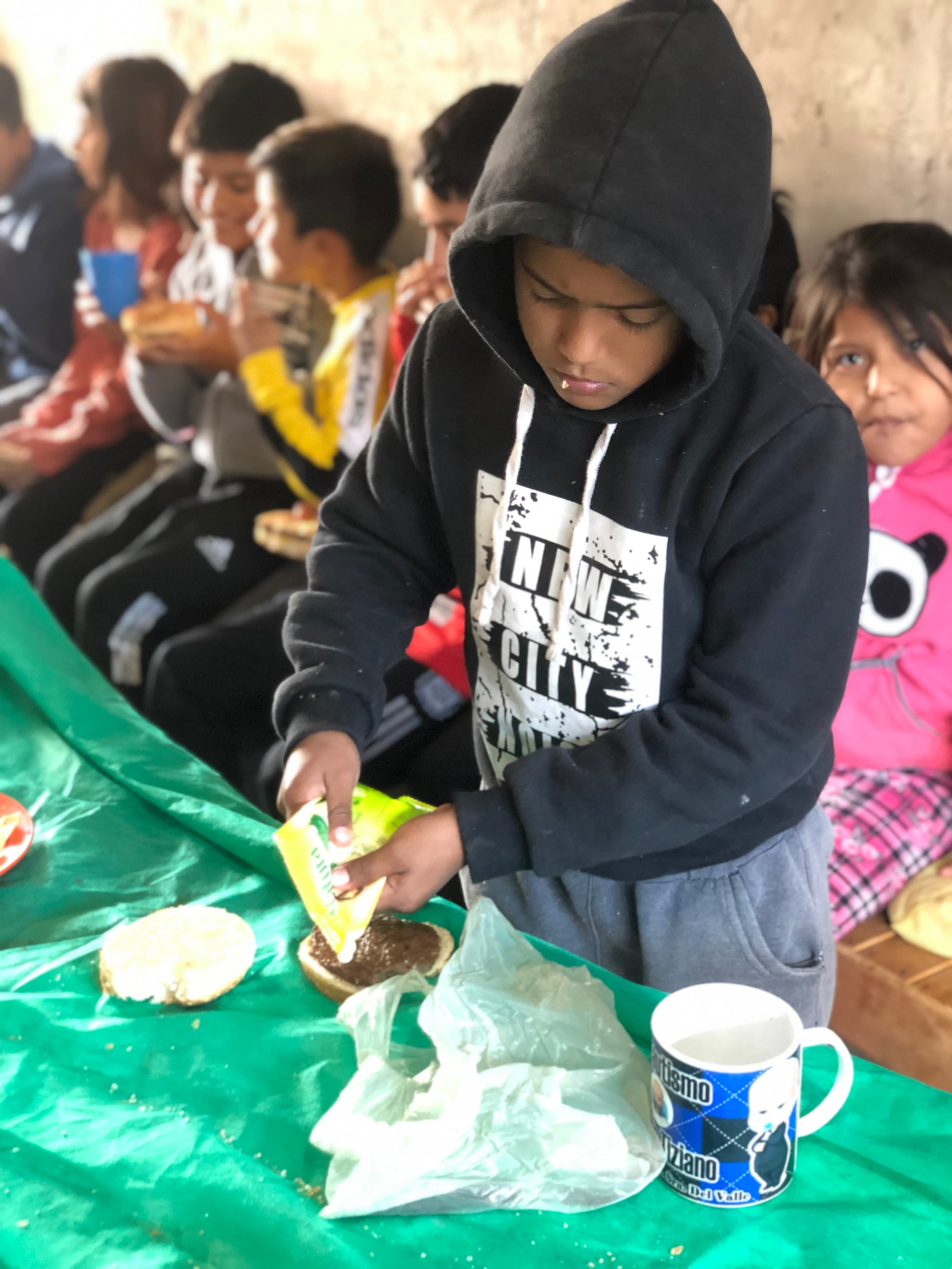 Chicos merendando pan con pancho y torta en el merendero