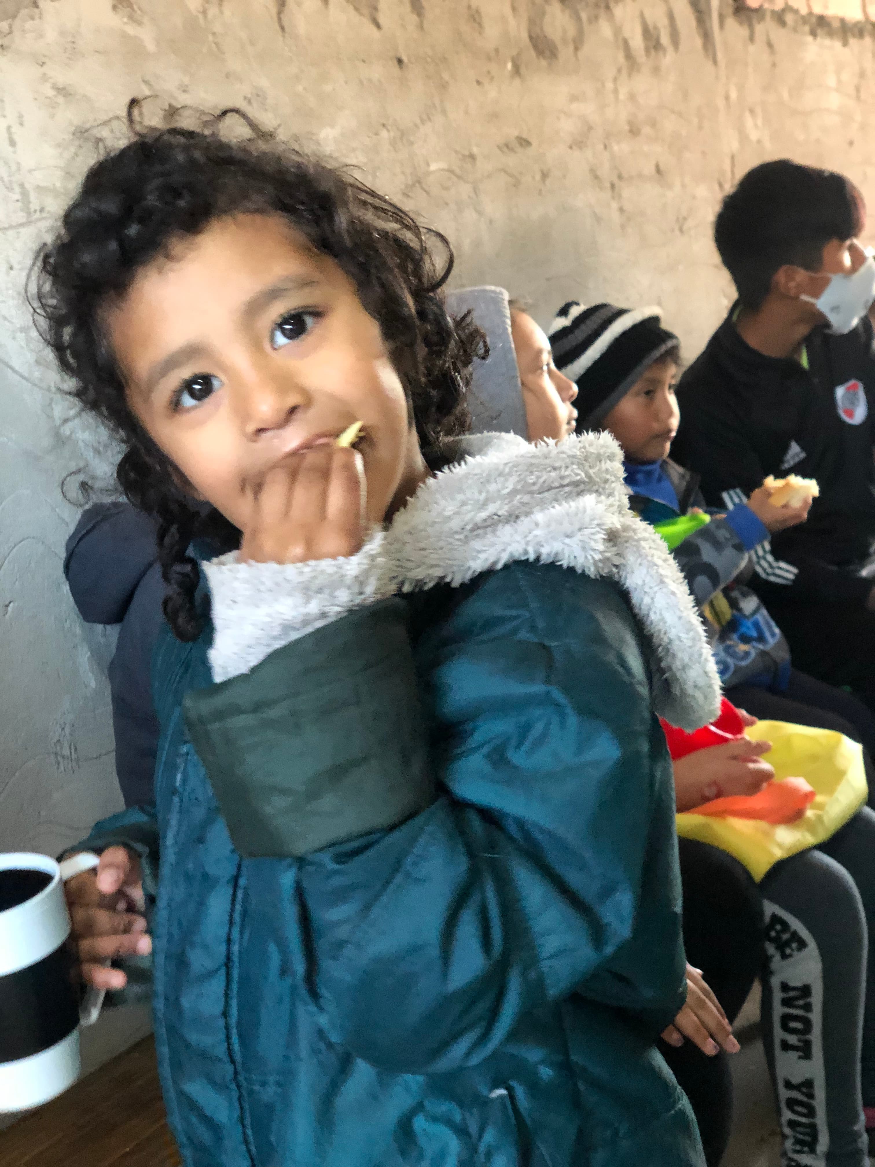 Chicos merendando pan con pancho y torta en el merendero